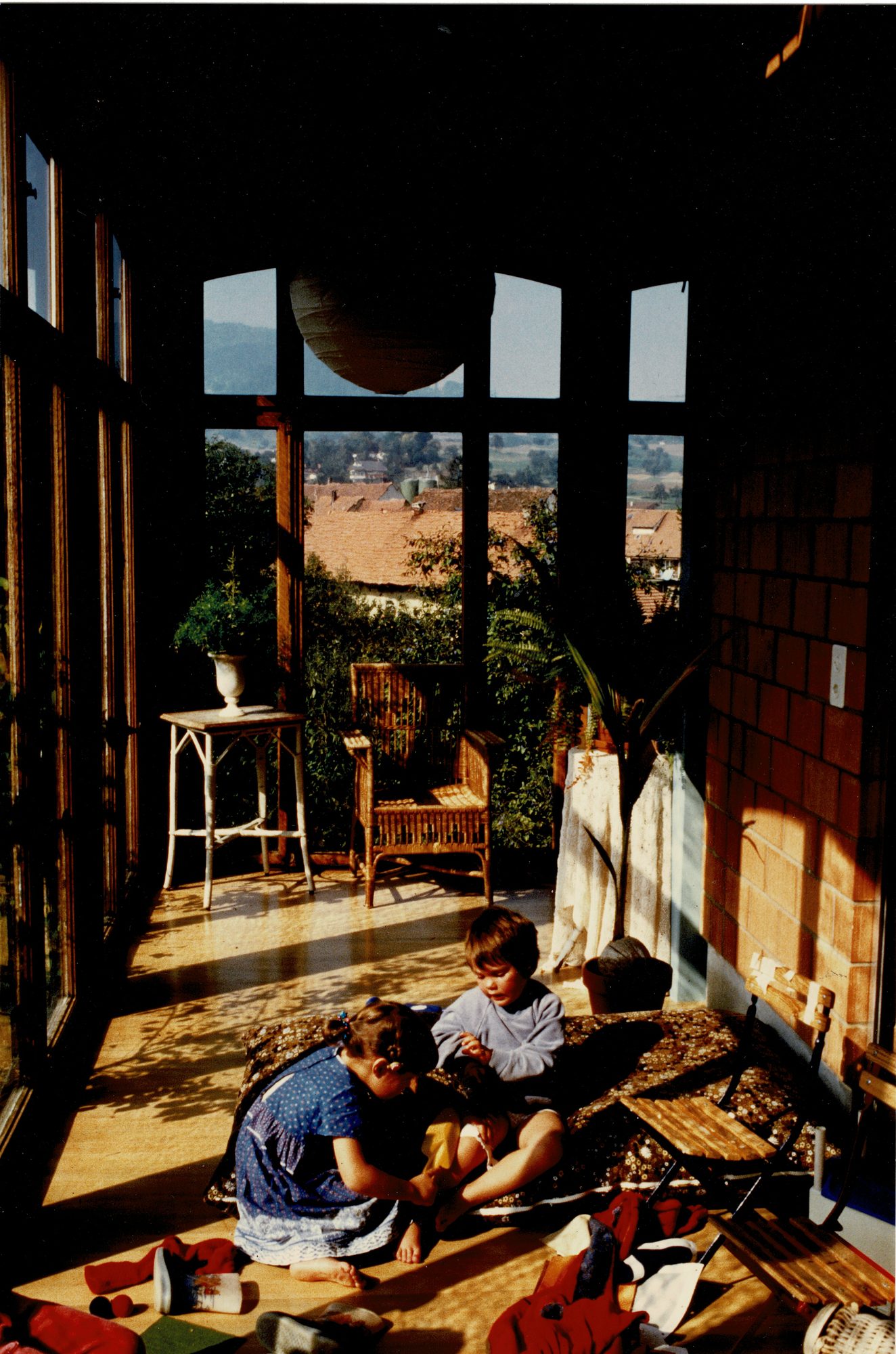 Kinder im Wintergarten des Wohnhauses mit Blick über das Dorf
